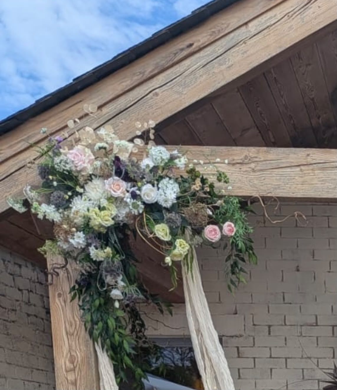 Floral swag and drapes across an outdoor timber arbour