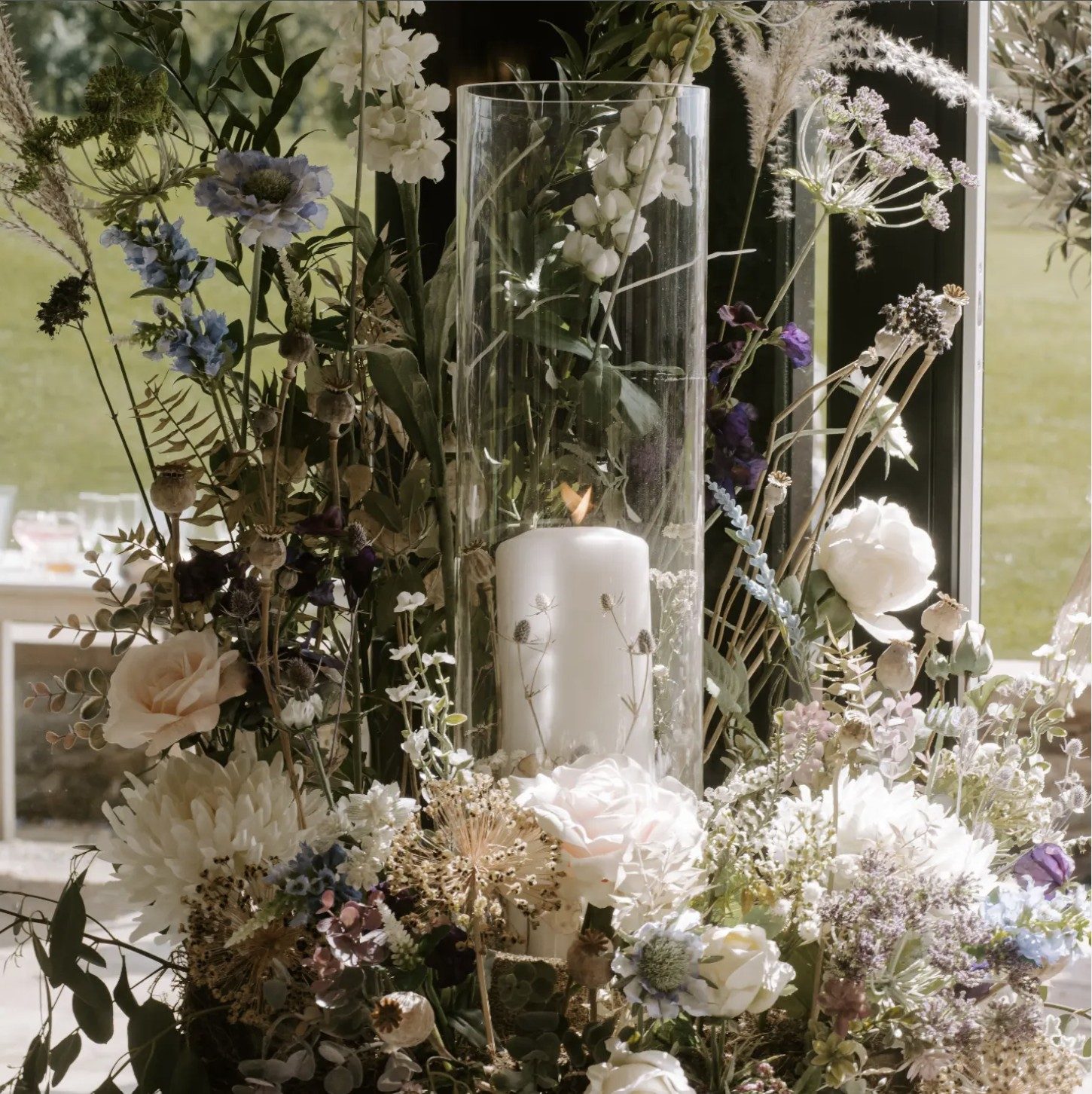 Close up of an arrangement mixing silk roses and dahlias with dried poppy heads, allium and grasses
