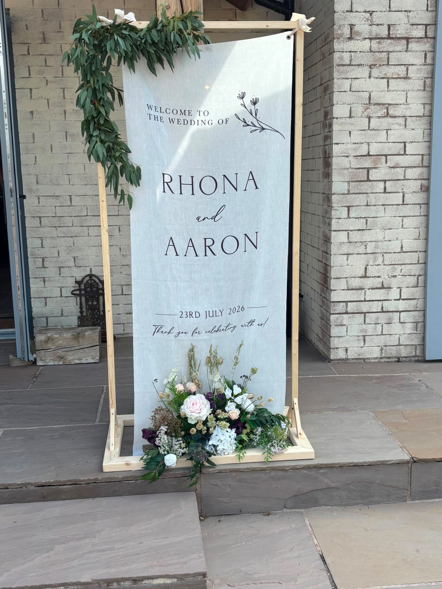 Linen welcome sign with a eucalyptus garland and floral base